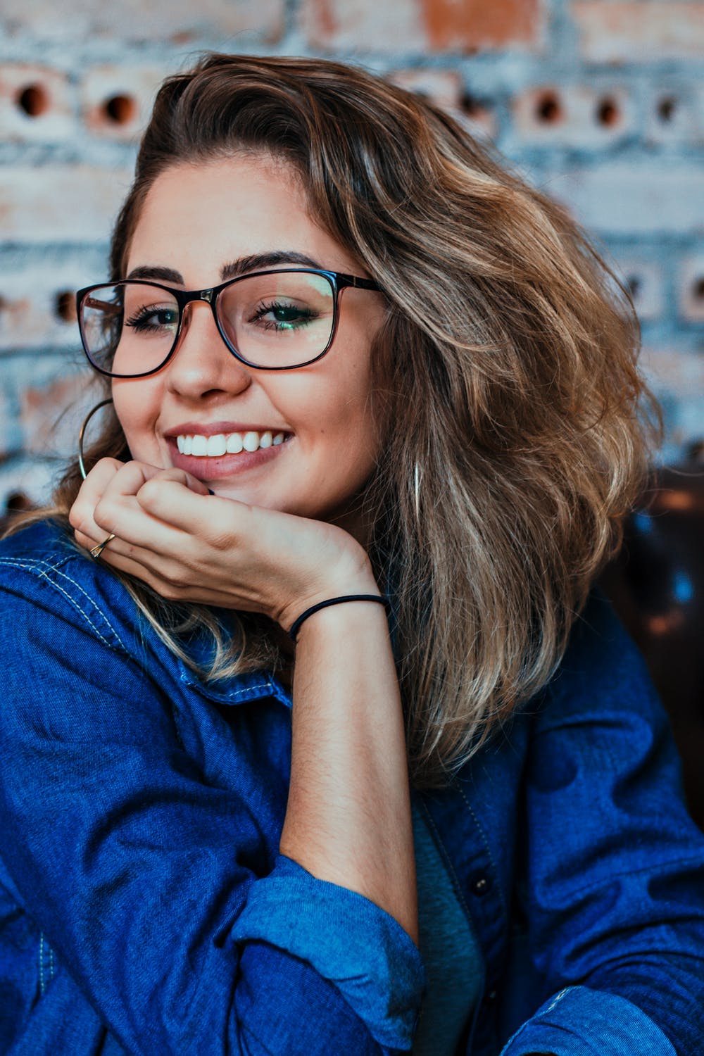 lady in a blue shirt wearing glasses and smiling
